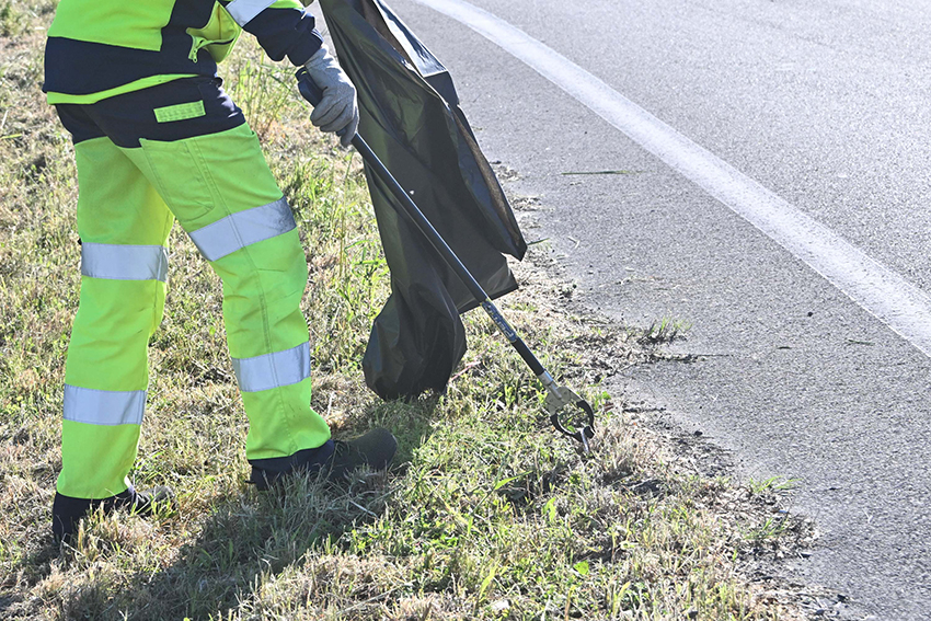 Un agent enlevant des déchets au bord de la route - Agrandir l'image (fenêtre modale)